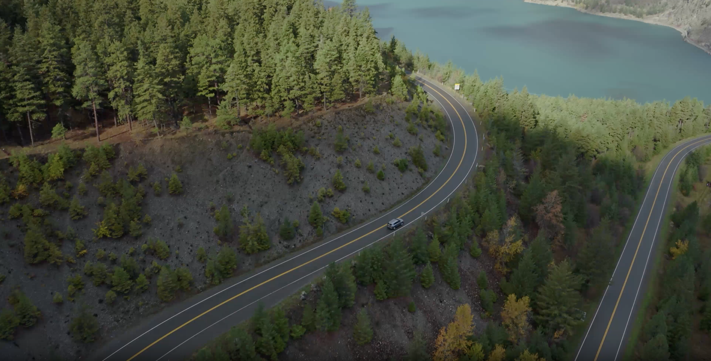 A car driving around a cliff against the water in BC, Canada